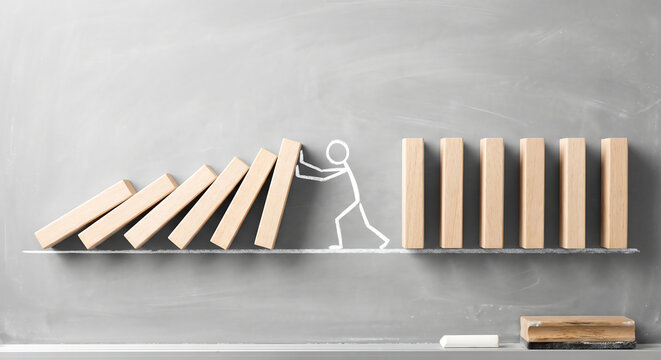 Chalk drawn stickman stopping falling wooden domino blocks on a blackboard for crisis management, risk prevention, and business intervention concept