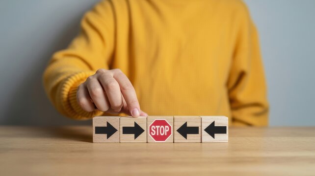 Hand stopping directional arrows with wooden blocks illustrating decision making and business strategy