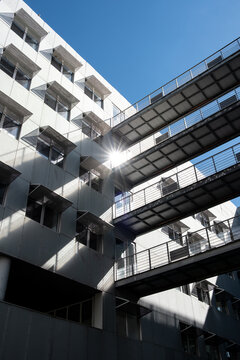 From an upward courtyard view in La Confluence, skybridges cross between facades as sunlight traces walkways and layered geometry above Lyon, France