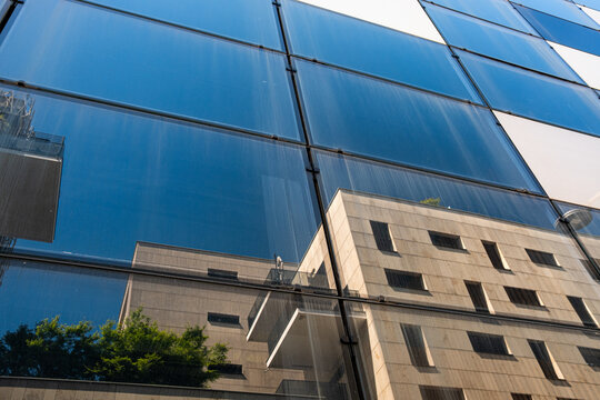 Neighboring architecture appears across a reflective glass facade in La Confluence, where blue windows shape an abstract reflection in Lyon, France