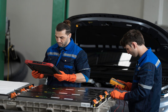 EV car repair service. Team of mechanic inspecting electric motor and inverter diagnostics, check, battery concern or repair