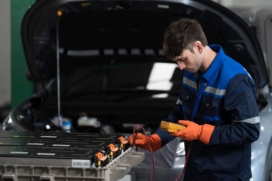 EV car maintenance garages. Technician diagnosing electric car vehicles battery, high-voltage battery service and general electric vehicle care at auto workshop