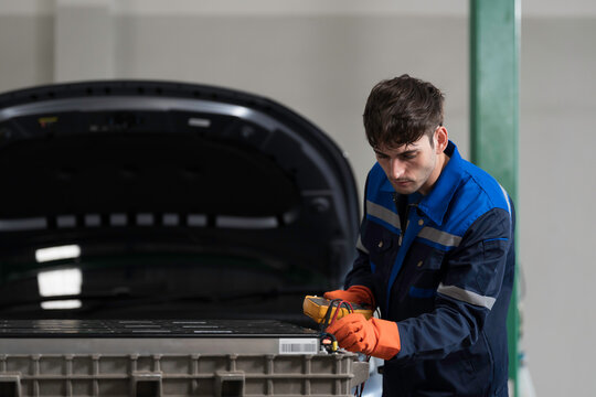 EV car maintenance garages. Technician diagnosing electric car vehicles battery, high-voltage battery service and general electric vehicle care at auto workshop