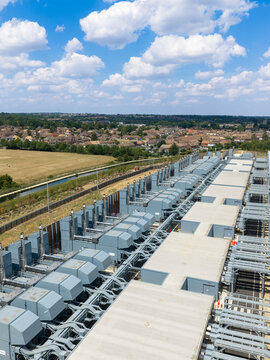 Aerial view of a large data center facility with rows of cooling units and industrial infrastructure situated near a suburban area in the United Kingdom.