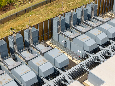Aerial view of a data center with large industrial cooling units and metal piping in the United Kingdom.