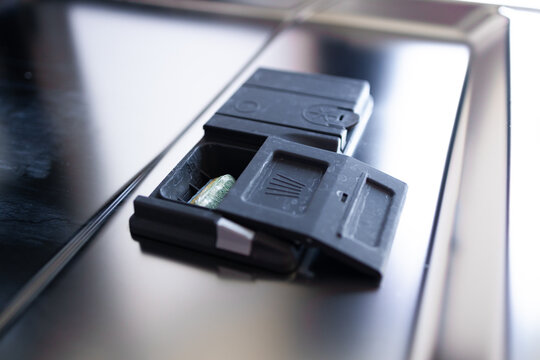 Close-up of an open small black plastic latch or holder attached to a glossy metal and glass panel. Industrial detail, electronic equipment installation or car interior component concept with
