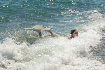 Swimmer with flippers floating through ocean waves during sunny day at the beach © svetograph