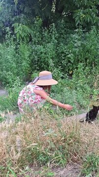 Child walks and explores nature in garden wearing a hat and dress
