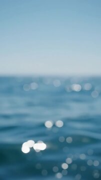 Vertical out of focus close up of ocean water surface glittering under bright direct sunlight. Fresh serene summer sea background for reels.
