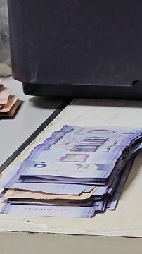 Stacks of UAE dirham banknotes in various denominations, including green and brown bills, lying on an office desk surface