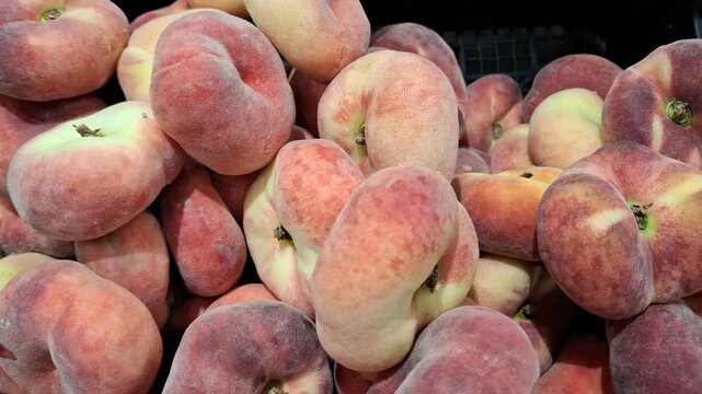 Ripe pink flat fig peaches arranged in a produce market, sweet summer fruit, healthy food choice, farm harvest, natural freshness and nutrition.