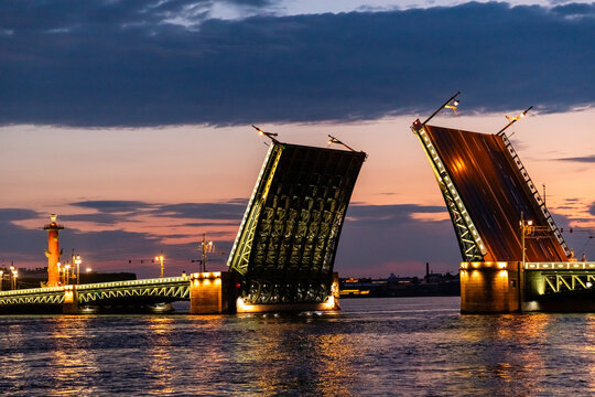 Illuminated Palace Drawbridge opens during white nights over Neva river, engineering architecture in cityscape. Dvortsovy bridge - symbol of St. Petersburg. Travel agencies, guides, tour operators