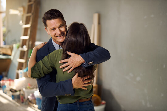 Happy couple embracing at construction site of their new apartment.