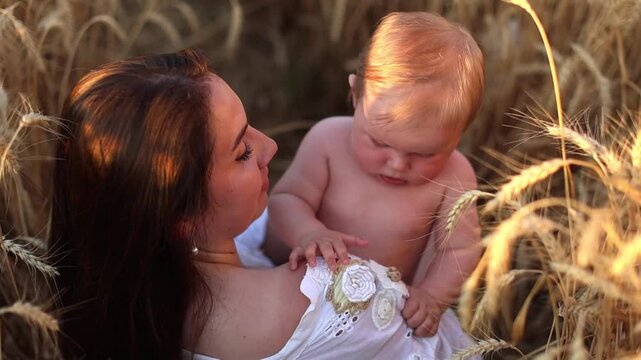 A mother tenderly kisses her seven-month-old son in a wheat field