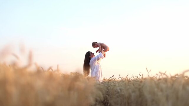 A mother tosses her seven-month-old son over her head in a wheat field