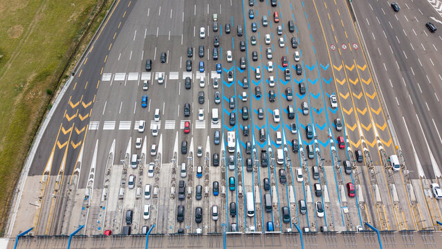 Aerial view of traffic queuing at the toll barrier on the Autostrada A1, featuring multiple lanes, road markings, and vehicles in Melegnano, Lombardy, Italy.