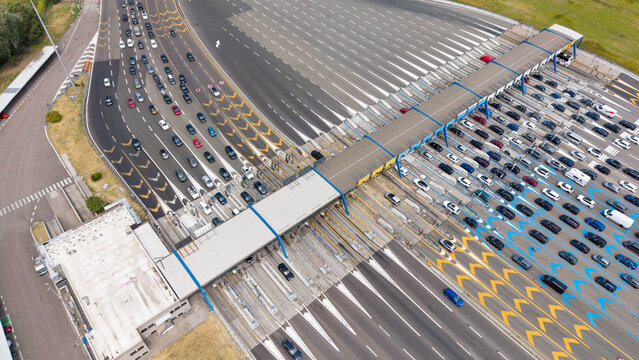Aerial view of the Melegnano toll barrier on the Autostrada A1 with numerous vehicles queuing through the toll gates, showcasing highway infrastructure in Melegnano, Lombardy, Italy.