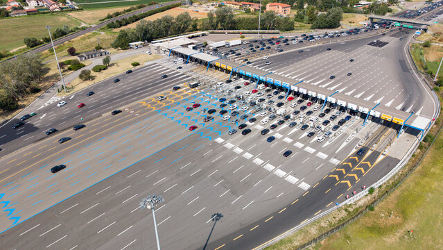 Aerial view of traffic crossing the southern Milan toll barrier on Autostrada A1, highlighting transportation infrastructure and surrounding landscape in Melegnano, Lombardy, Italy.