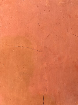 Close-up of a rustic terracotta clay wall texture with subtle fine cracks and a matte finish.