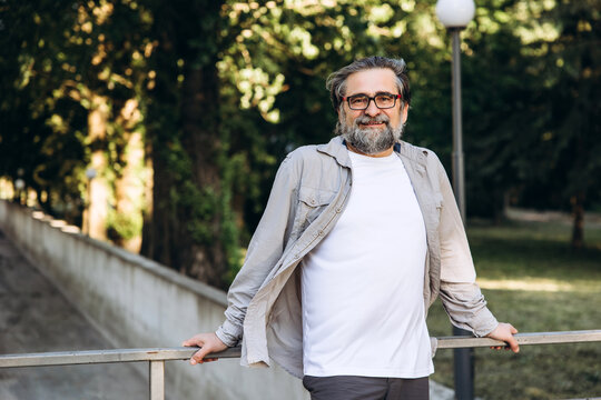 Smiling mature man with beard and glasses relaxing outdoors