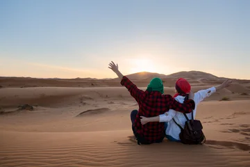 Loving couple sitting  with arms up in the Sahara Desert. Morocco. © xamnex
