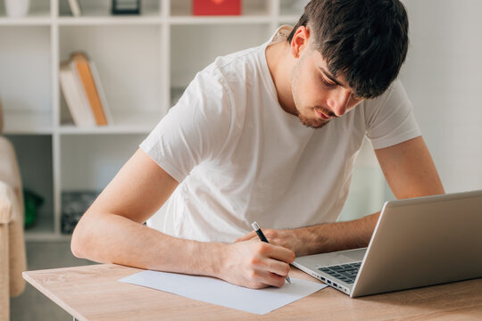Young student at home desk with laptop working or taking exams remotely in the online course