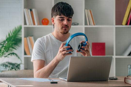 Online student putting on headphones at their desk with their laptop to start the course