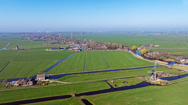 Aerial view of traditional Dutch windmills situated along canals in the lush green polder landscape of Oud-Alblas, South Holland, Netherlands.