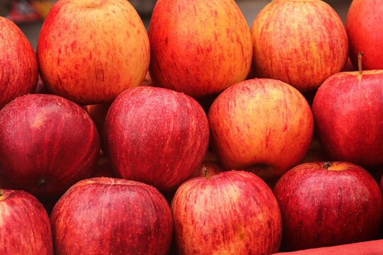 Pile of Fresh Red Gala Apples in a Wooden Crate. Close Up of Ripe Apples Background at a Farmers Market. Vibrant Red and Yellow Apples Textures and Patterns.j
