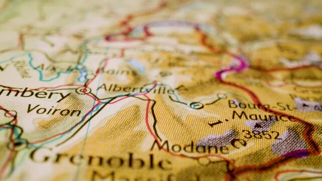 Gliding macro view over physical atlas map leading to Mont Blanc, France