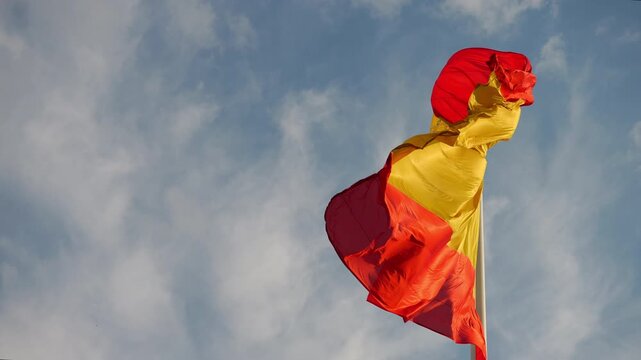 Spanish flag waving in the wind against a blue sky