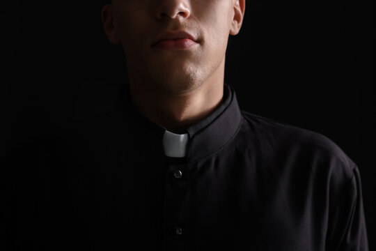 Priest in cassock on black background, closeup
