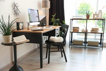 Fototapeta premium Stylish table with computer, chair and shelving unit in home office. Interior design