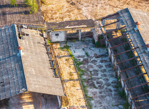 Aerial view of the historic Dwor Lublewo estate featuring dilapidated farm buildings with exposed roof beams and overgrown courtyard in Lublewo Leborskie, Wojewodztwo pomorskie, Poland.