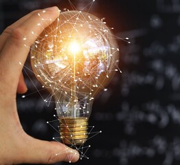 Hand cradles glowing bulb with digital network overlays. Light shines bright, symbolizing innovation and connection. Abstract lines form a web around the bulb © Issarawat Tattong