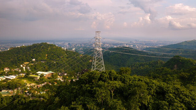 Aerial view of Busay featuring a power transmission tower amidst lush green hills with the Cebu City skyline in the background, Cebu City, Central Visayas, Philippines.