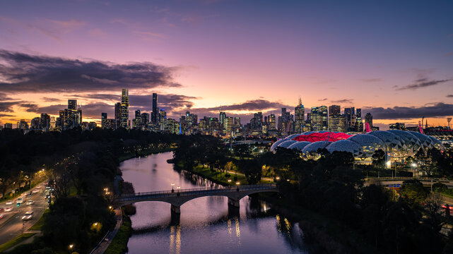 Aerial view of AAMI Park and the Melbourne skyline illuminated at sunset with the Yarra River and a bridge in the foreground in Melbourne, Victoria, Australia.