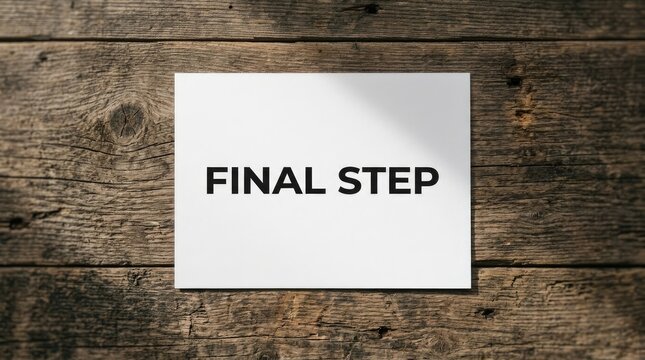 Final step sign printed on white paper resting against a textured dark brown wooden plank surface
