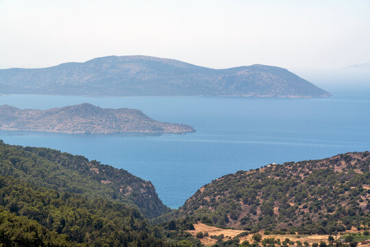 View of hills of Rhodes and islands near the coast with blue water and clear sky during daytime in a scenic location