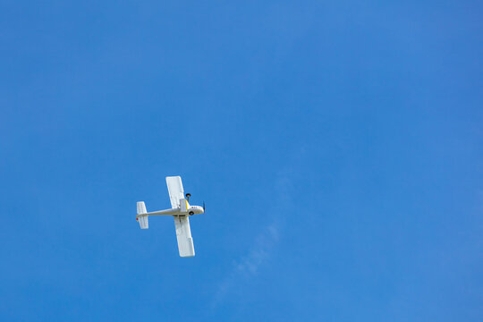 View of a small white airplane flying against a clear blue sky in Vilnius, Vilnius County, Lithuania.