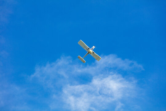 View of a small light aircraft flying against a clear blue sky with scattered clouds over Vilnius, Vilnius County, Lithuania.