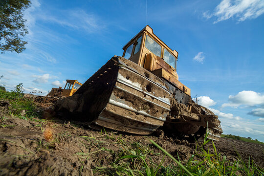 View of a yellow bulldozer on muddy ground under a bright blue sky in Kelme, Siauliai County, Lithuania.