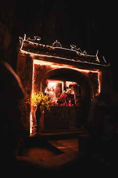 View of The Marble Mountains featuring an illuminated shrine with traditional architecture, floral offerings, and warm ambient lighting inside a cave in Da Nang, Da Nang, Vietnam.