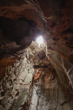 View of the natural light streaming through a hole in the ceiling of a limestone cave at The Marble Mountains in Da Nang, Da Nang, Vietnam.