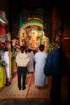 View of people praying before a golden statue inside a temple at The Marble Mountains in Da Nang, Da Nang, Vietnam.