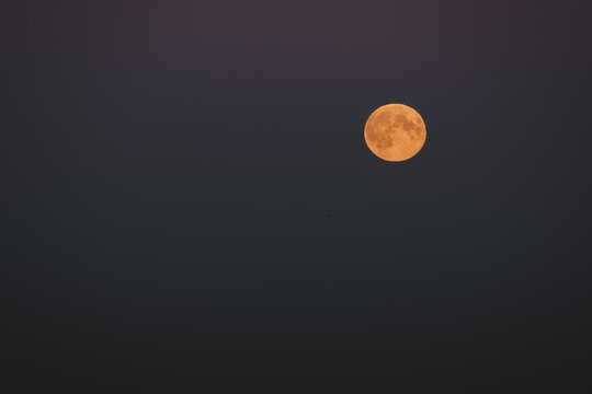 View of a full moon glowing with an orange hue in the dark night sky over Merikula, Harju maakond, Estonia.