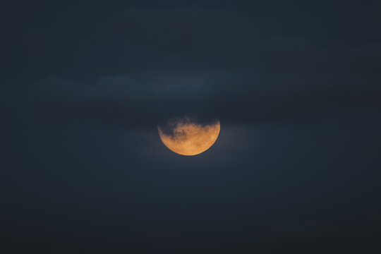 View of the moon partially obscured by dark clouds at night in Merikula, Harju maakond, Estonia.