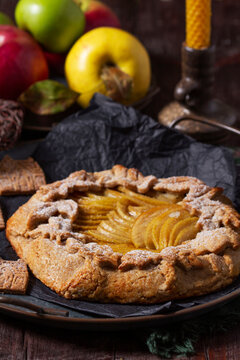 Apple galette, gingerbread houses, and apples on a wooden background.