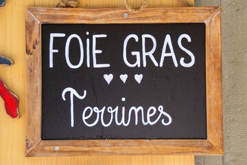 Rustic French chalkboard sign advertising foie gras terrines with handwritten text on wooden frame © Carsten