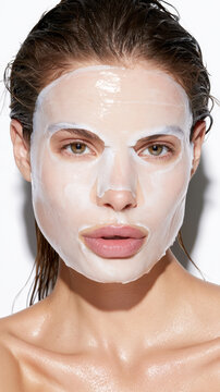 Young woman applying a hydrating sheet face mask for skin care treatment, focusing on beauty, wellness, and self care routines for glowing, refreshed skin